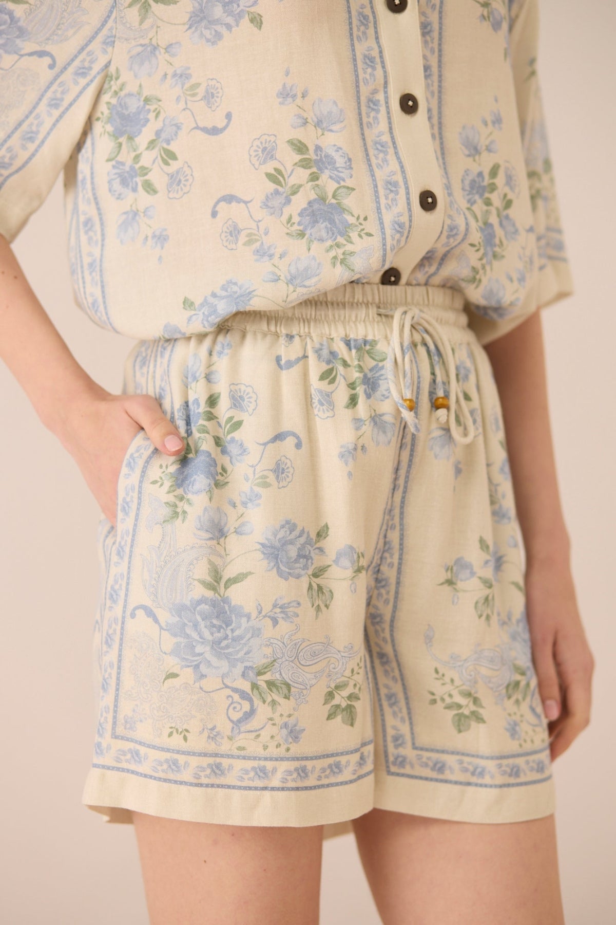 Person wearing a floral outfit with shorts and a top on a plain background Calling June