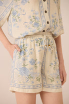 Person wearing a floral outfit with shorts and a top on a plain background Calling June