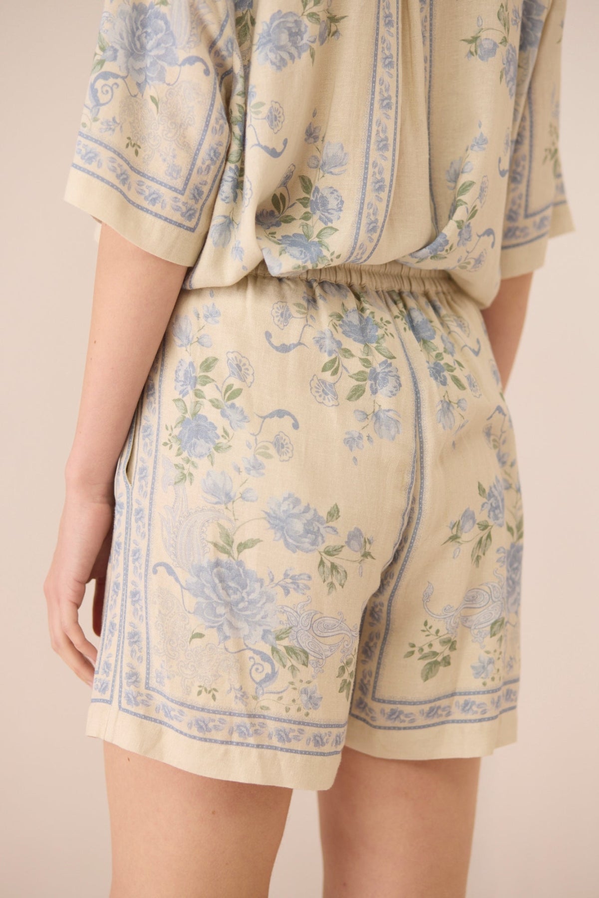 Beige outfit with blue floral pattern on a plain background Calling June