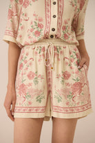 Person wearing a floral patterned outfit with a beige background Calling June