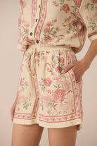 Person wearing a floral outfit with a beige background Calling June