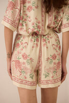 Person wearing a floral romper with a beige background Calling June