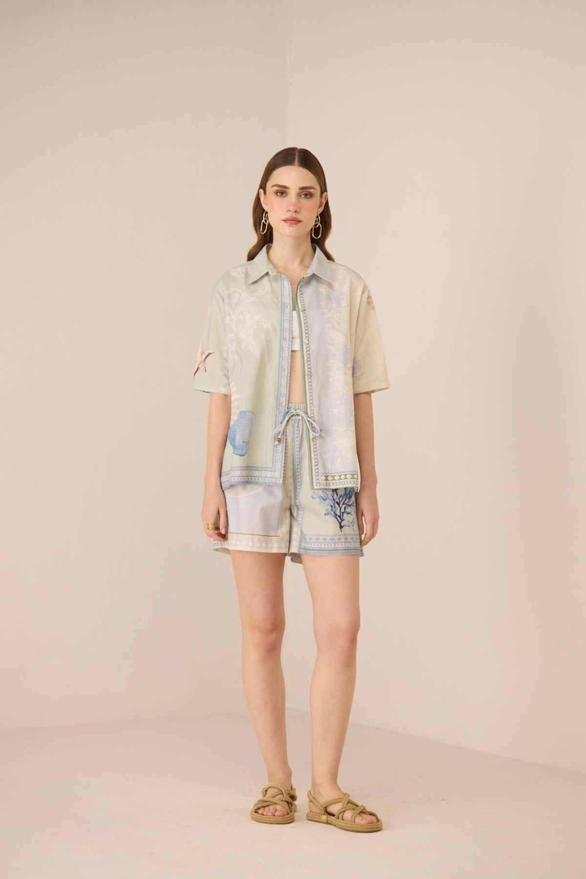 Woman wearing a light-colored outfit with denim accents on a beige background Calling June