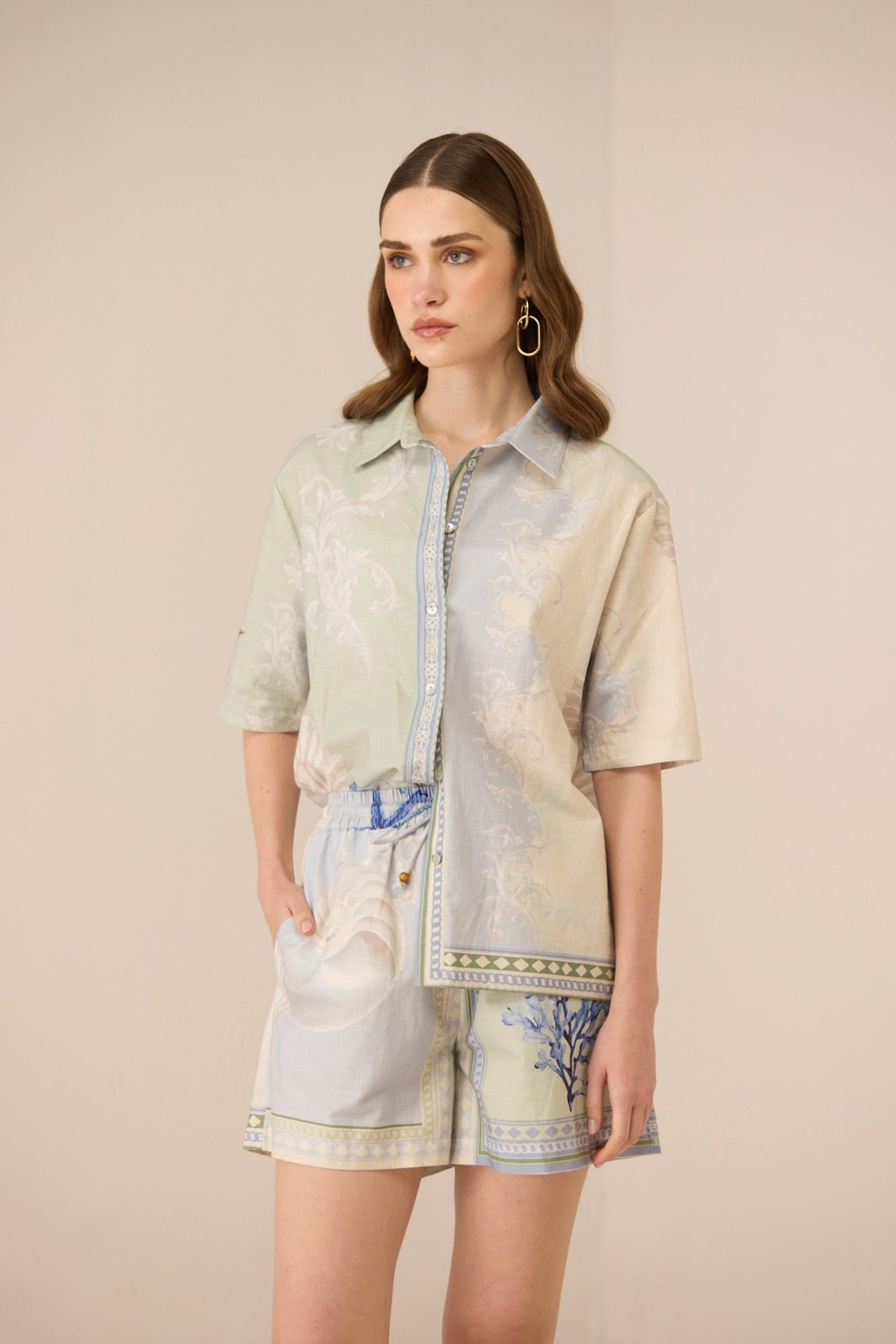 Woman wearing a patterned shirt and shorts on a beige background Calling June