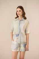 Woman wearing a patterned shirt and shorts on a beige background Calling June