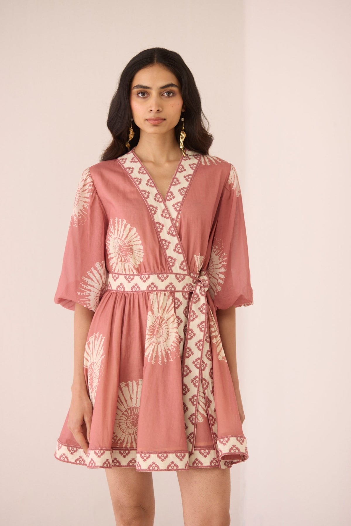 Woman wearing a pink dress with a geometric pattern on a plain background Calling June