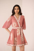 Woman wearing a pink patterned dress against a plain background Calling June