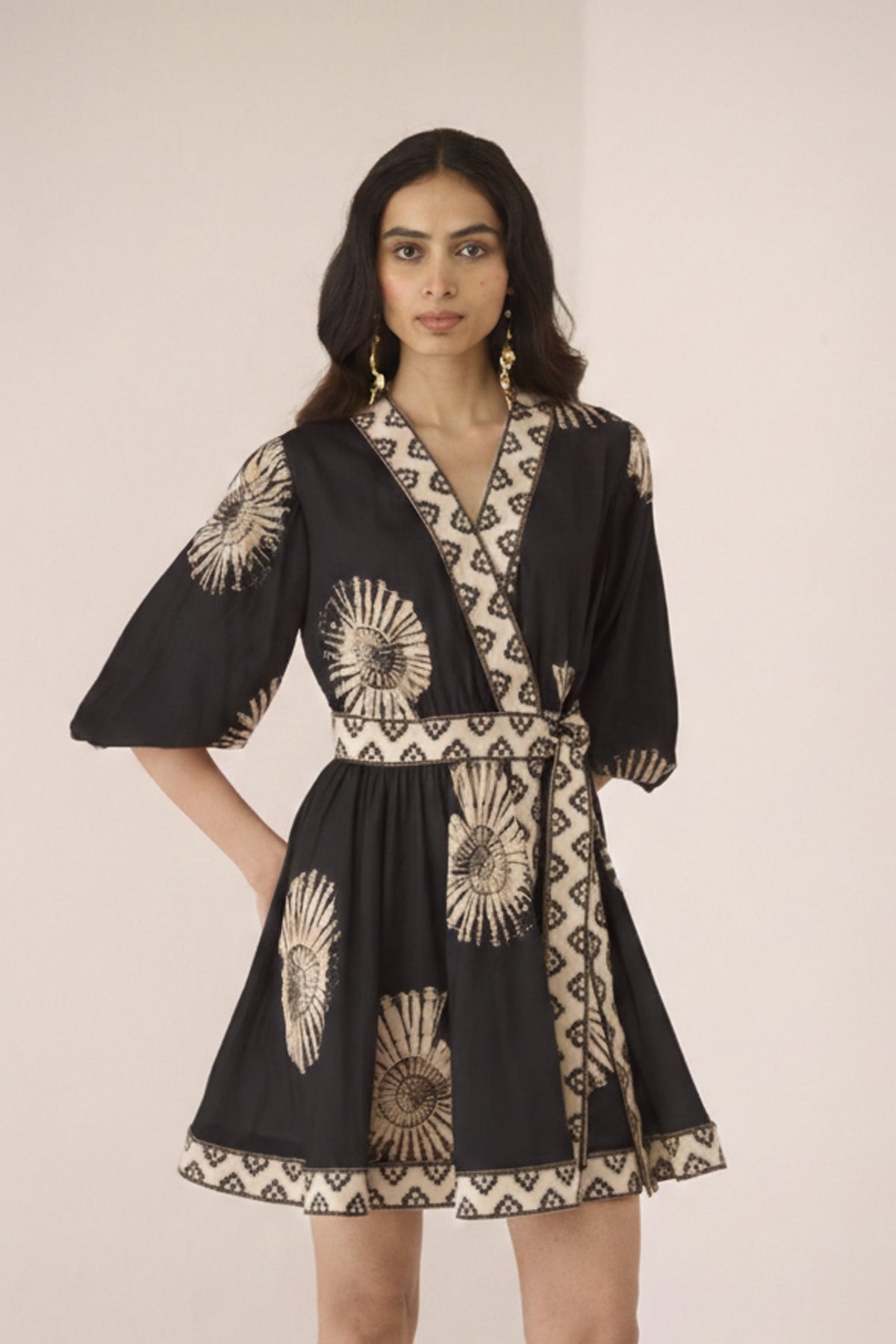 Woman wearing a black dress with gold patterns on a plain background Calling June