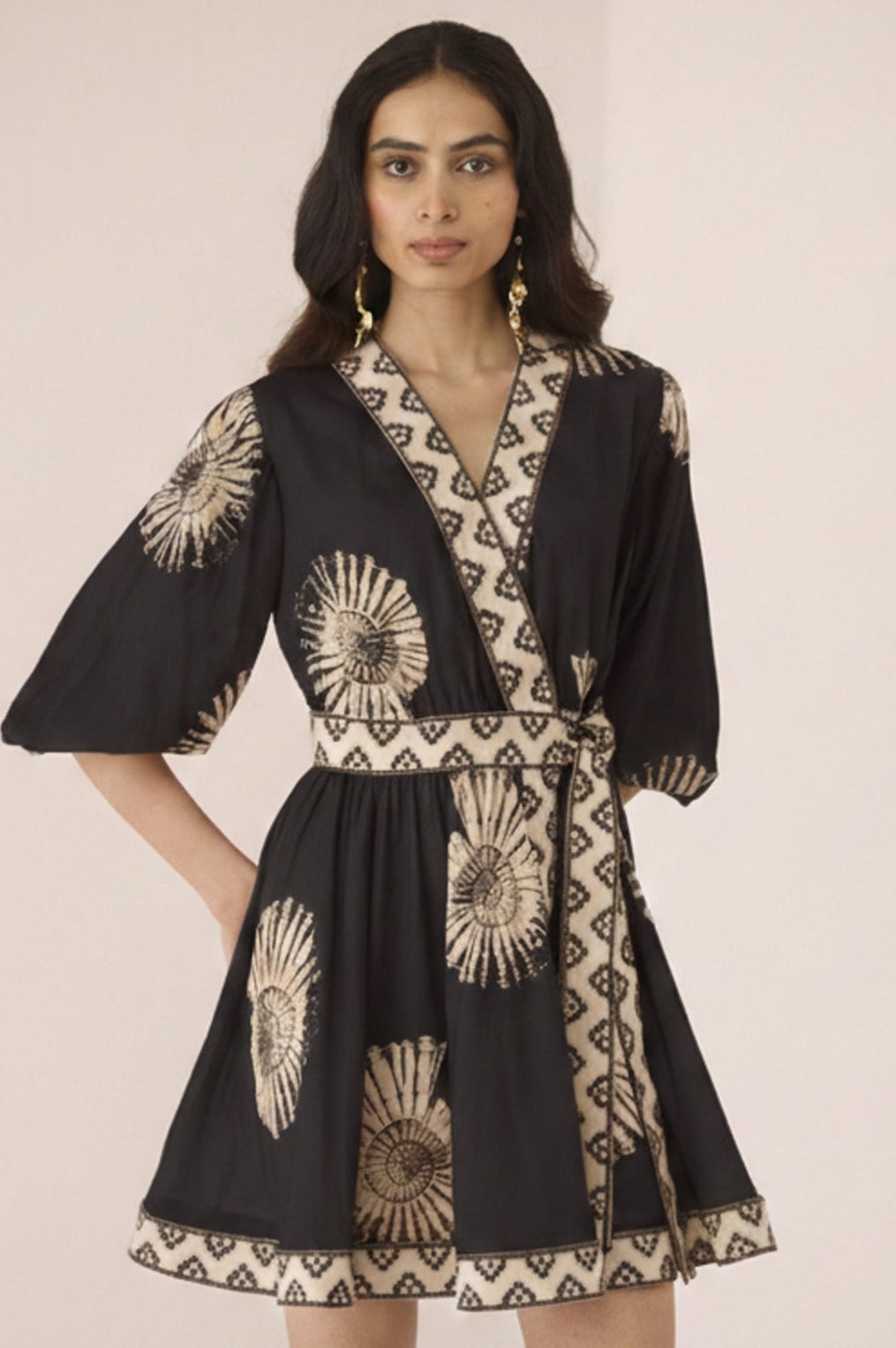 Woman wearing a black dress with gold patterns on a plain background Calling June