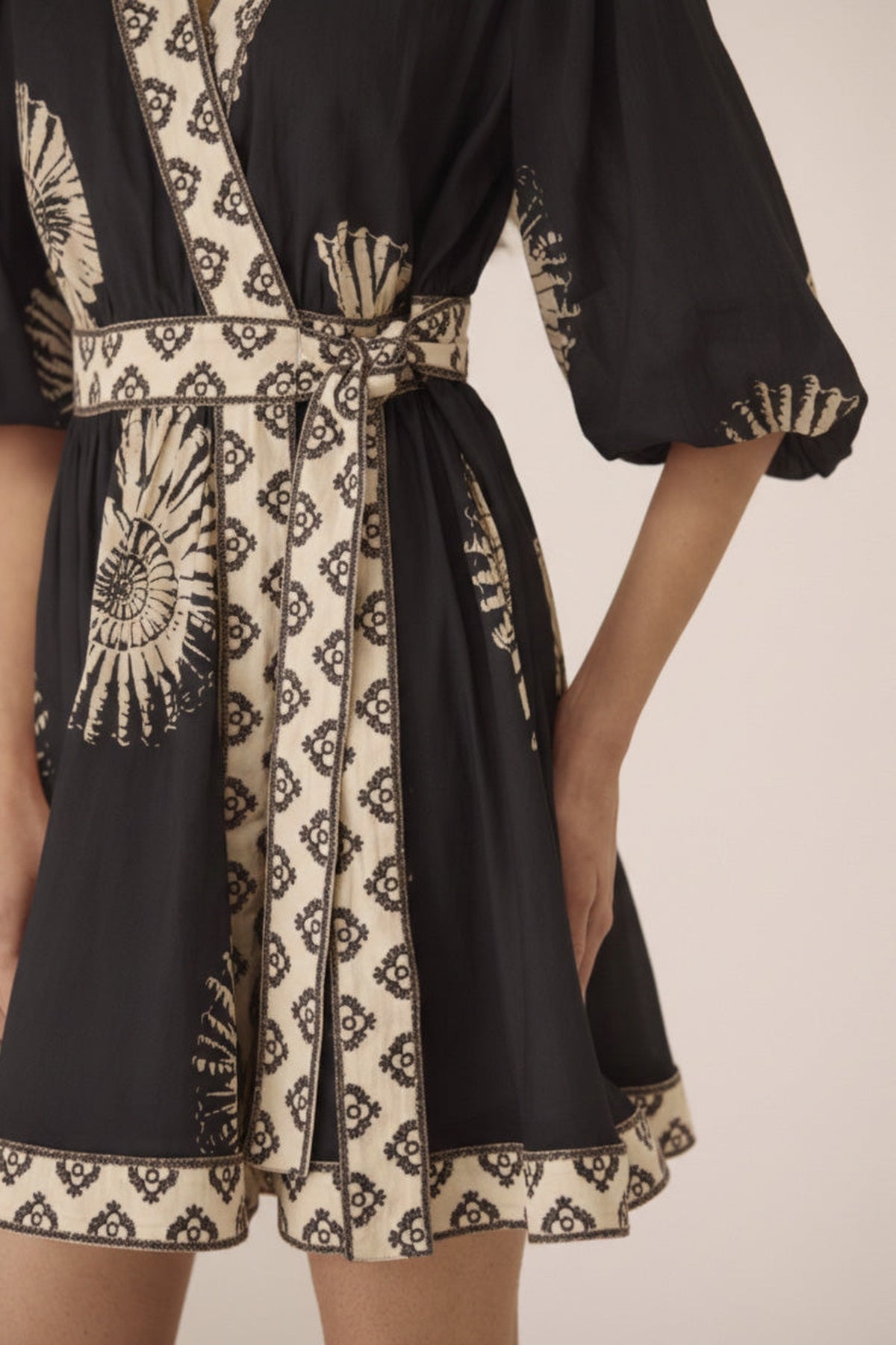 Black and beige patterned dress with a belt on a neutral background Calling June