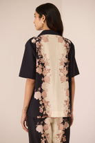 Woman wearing a black and beige floral outfit against a beige background Calling June