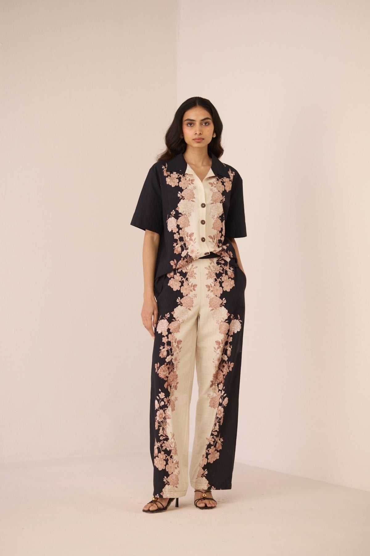 Woman wearing a black and white floral jumpsuit on a beige background Calling June