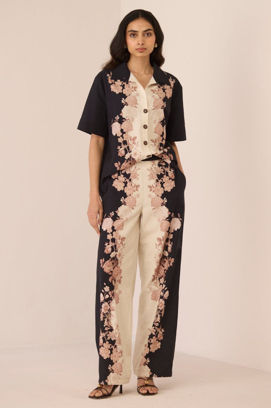 Woman wearing a black and white floral jumpsuit on a beige background Calling June