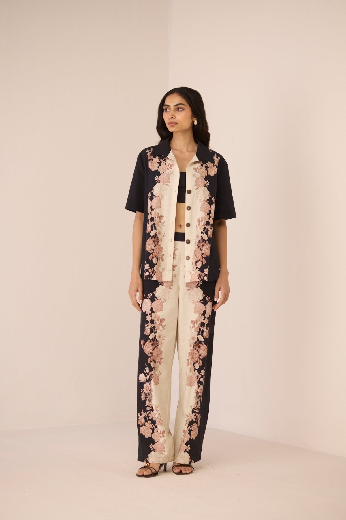 Woman wearing a black and white floral outfit on a beige background Calling June