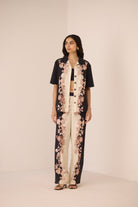 Woman wearing a black and white floral outfit on a beige background Calling June