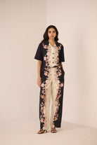 Woman wearing a black and white floral jumpsuit on a beige background Calling June