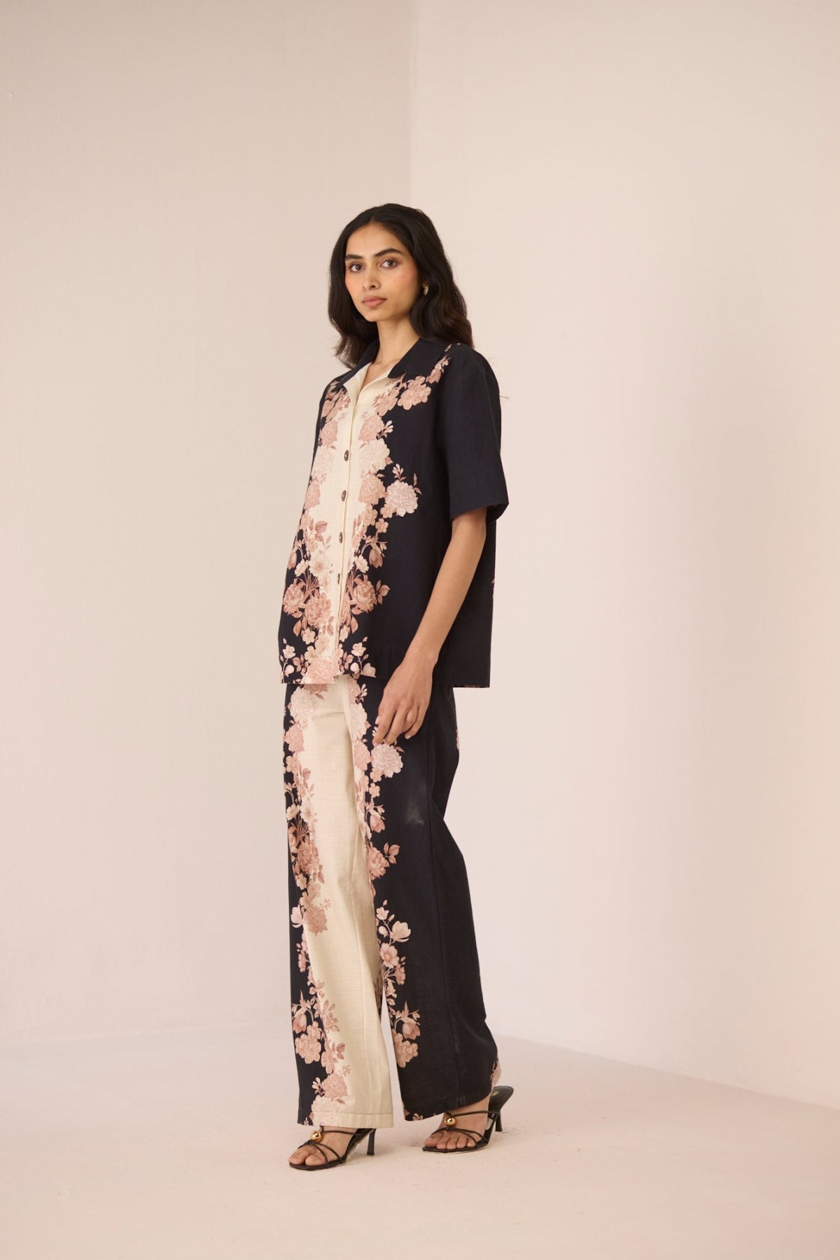 Woman wearing a black outfit with floral embroidery on a plain background Calling June