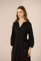 Woman wearing a black dress against a beige background Calling June