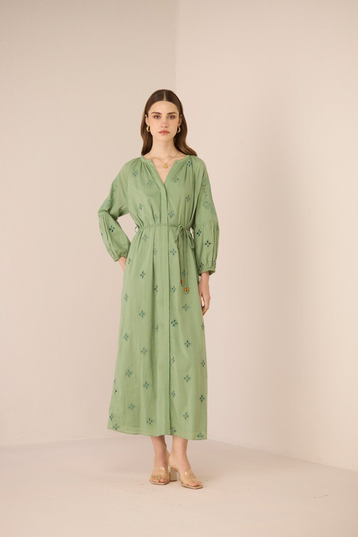 Woman wearing a green dress with floral patterns on a beige background Calling June