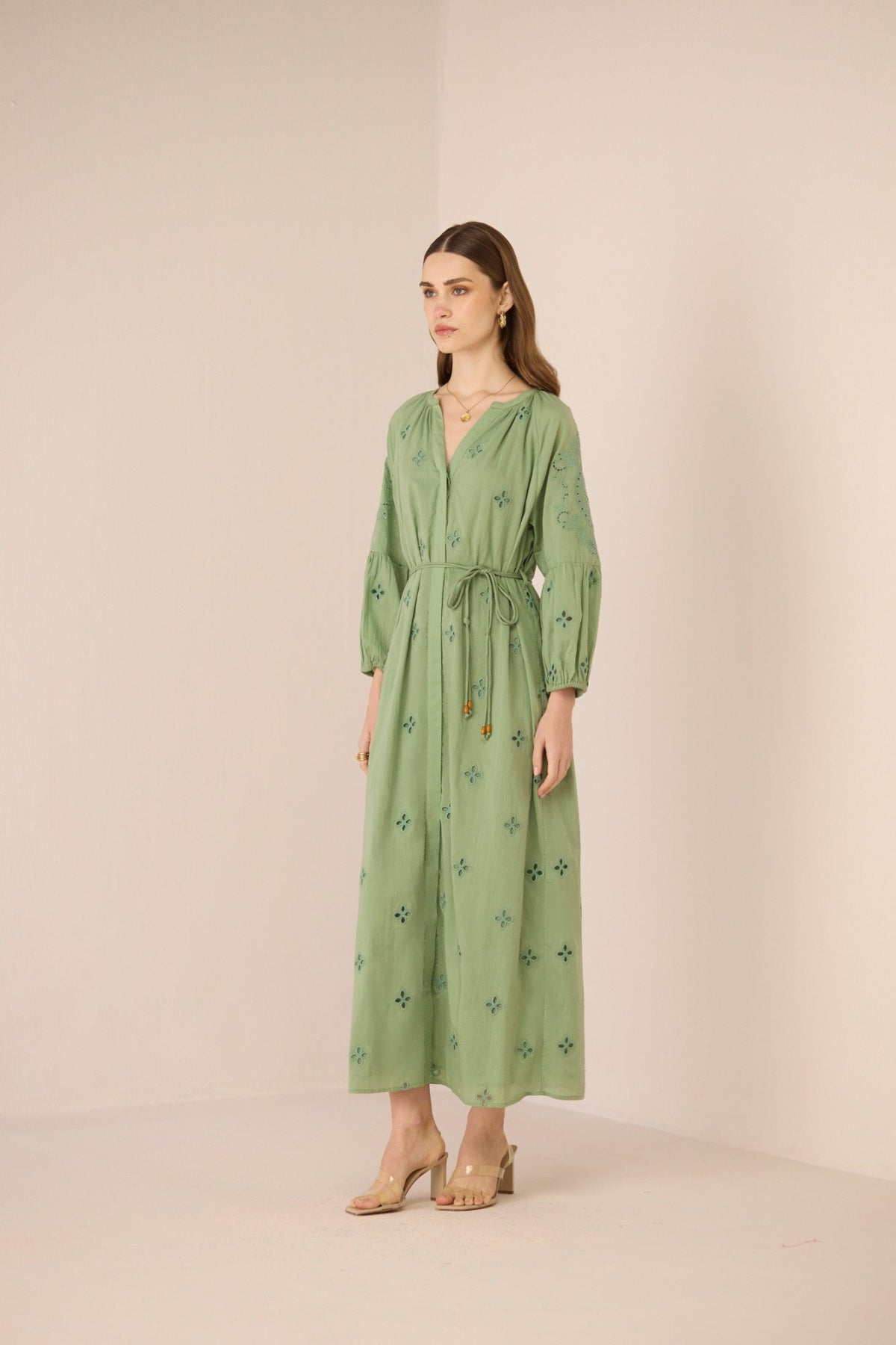 Woman wearing a green dress with floral patterns against a beige background Calling June