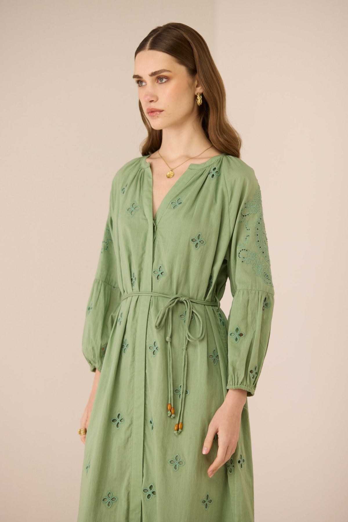 Woman wearing a green dress with floral patterns against a beige background Calling June