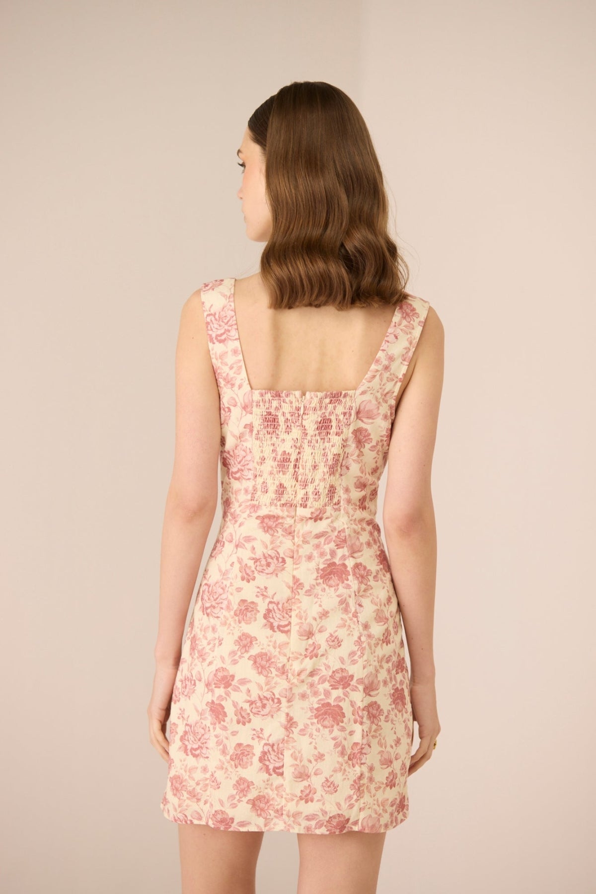 Woman wearing a floral dress against a beige background Calling June