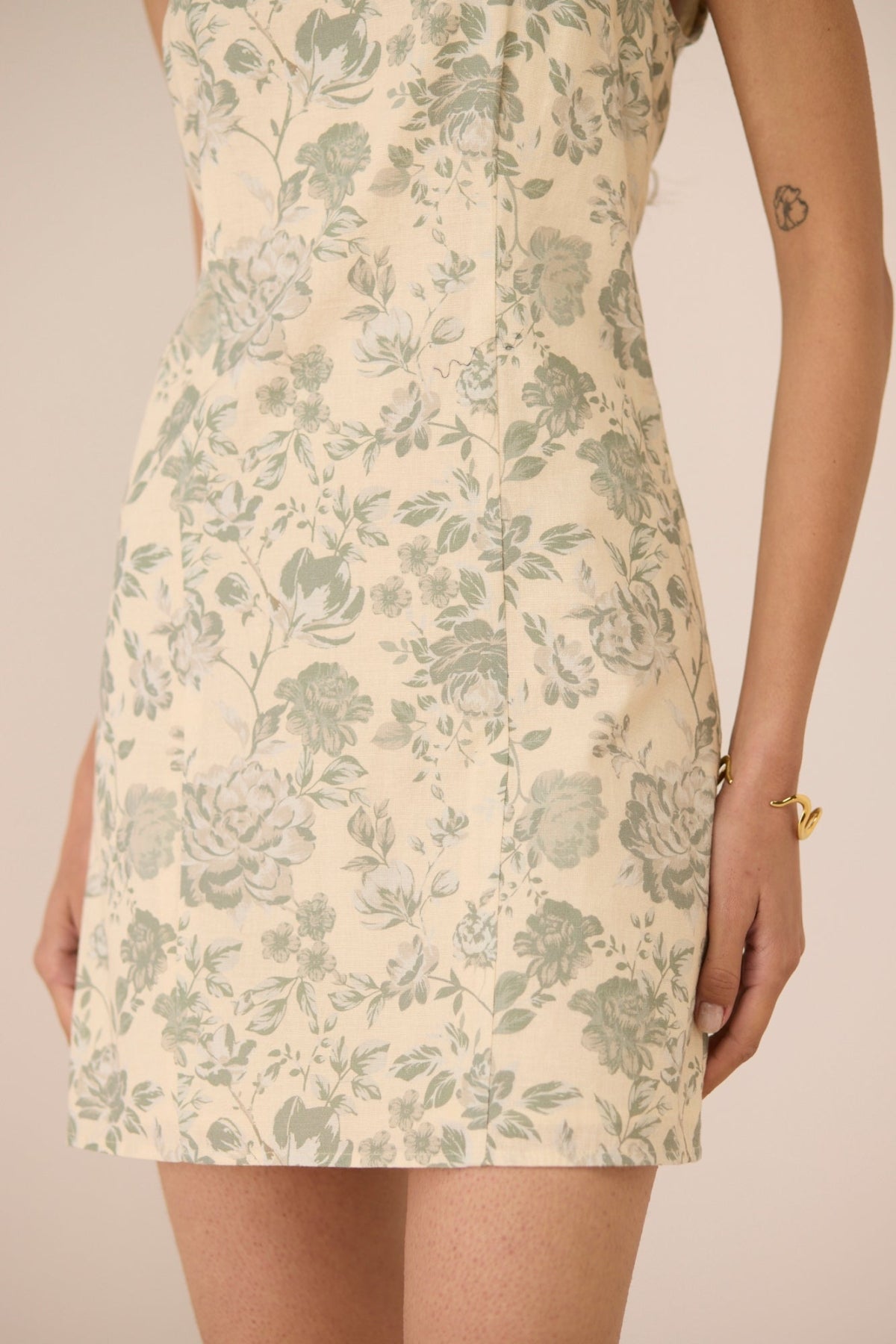 Beige dress with green floral pattern worn by a person on a beige background Calling June