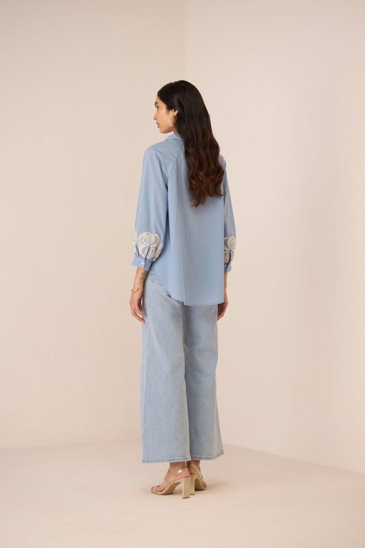 Woman wearing a light blue outfit with a matching top and pants on a beige background Calling June