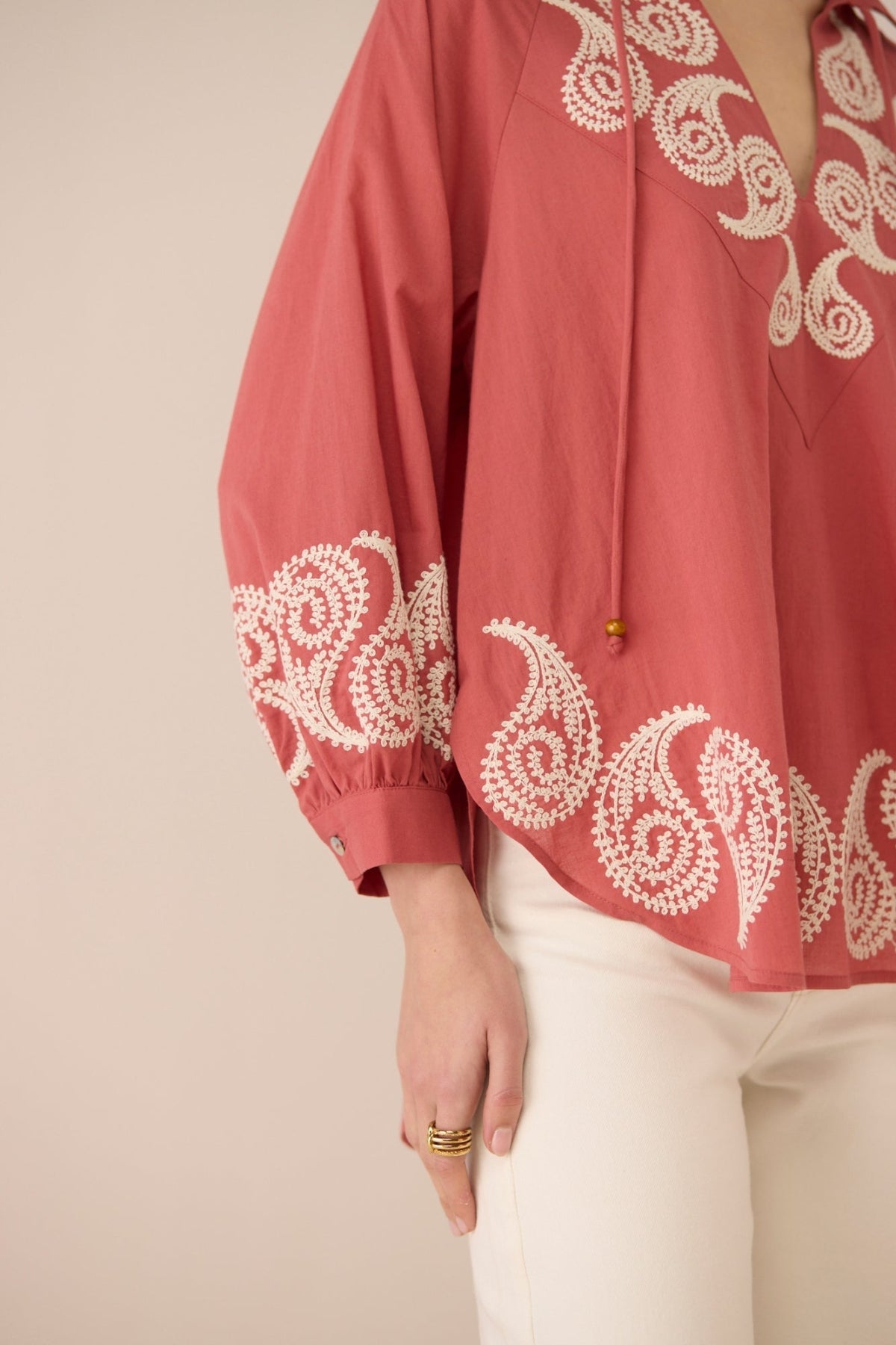 Red blouse with white embroidery on a beige background Calling June