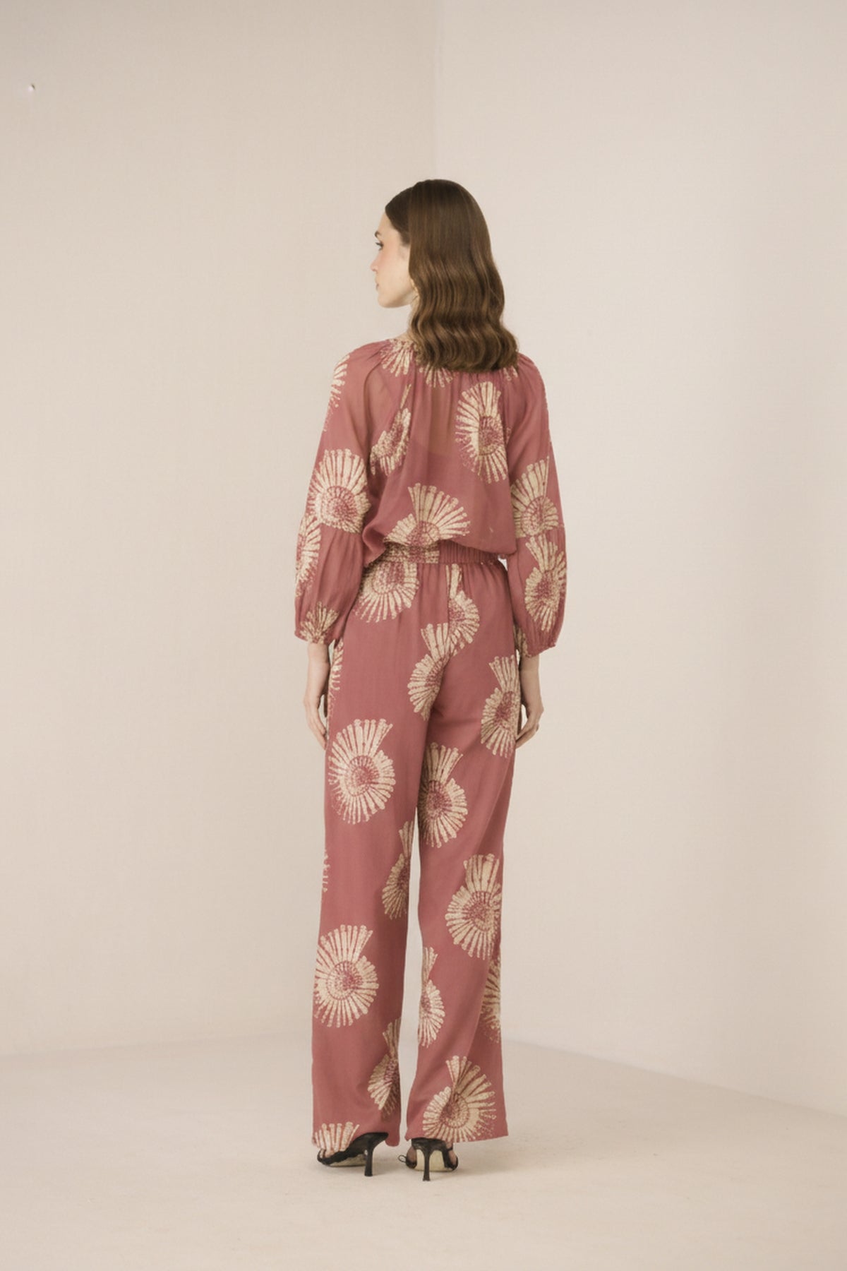 Woman wearing a pink floral outfit on a beige background Calling June