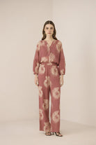 Woman wearing a pink floral jumpsuit on a beige background Calling June