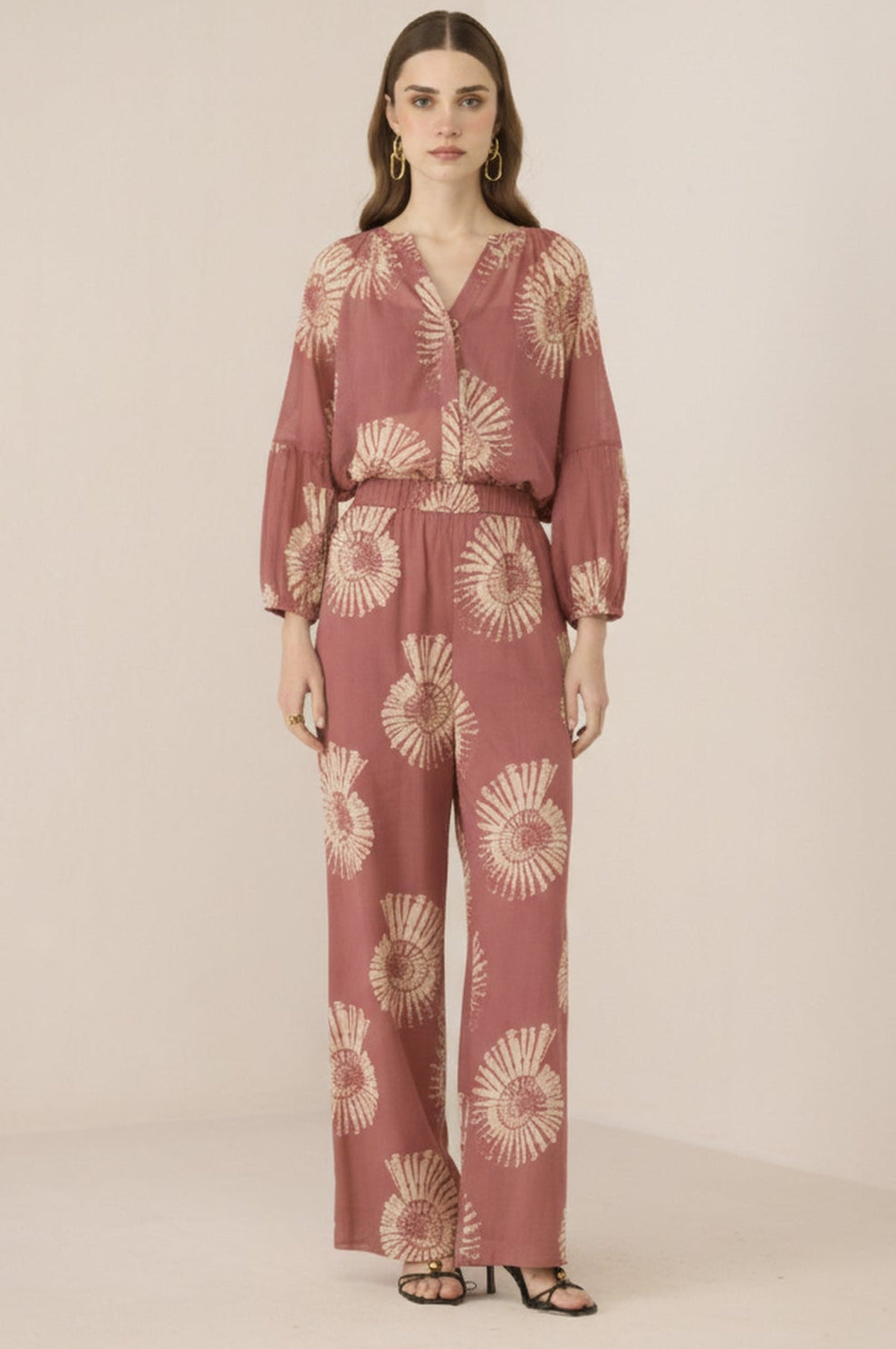 Woman wearing a pink floral jumpsuit on a beige background Calling June