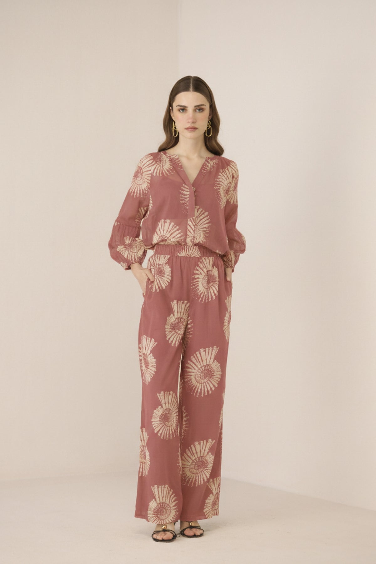 Woman wearing a pink floral jumpsuit on a beige background Calling June