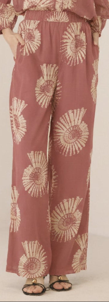 Woman wearing a pink floral jumpsuit on a beige background Calling June