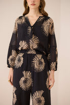 Woman wearing a black outfit with beige floral patterns on a beige background Calling June