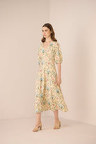 Woman wearing a floral dress against a plain background Calling June