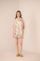 Woman wearing a floral dress with a matching jacket on a beige background Calling June
