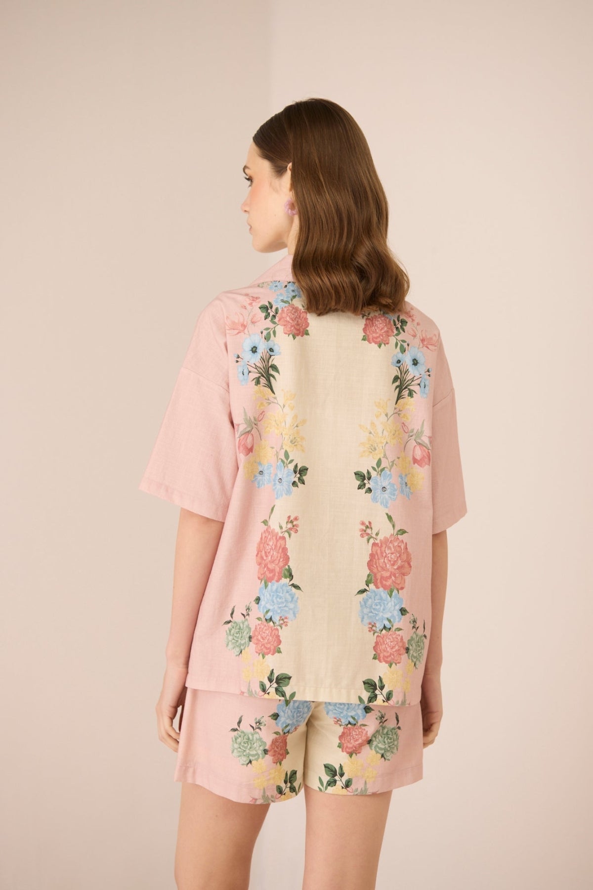 Woman wearing a floral kimono-style garment with a plain background Calling June