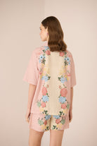 Woman wearing a floral kimono-style garment with a plain background Calling June