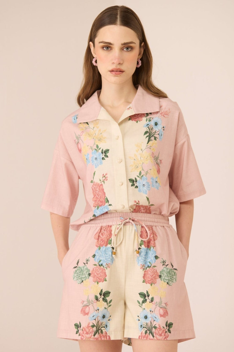 Woman wearing a pink floral outfit on a beige background Calling June