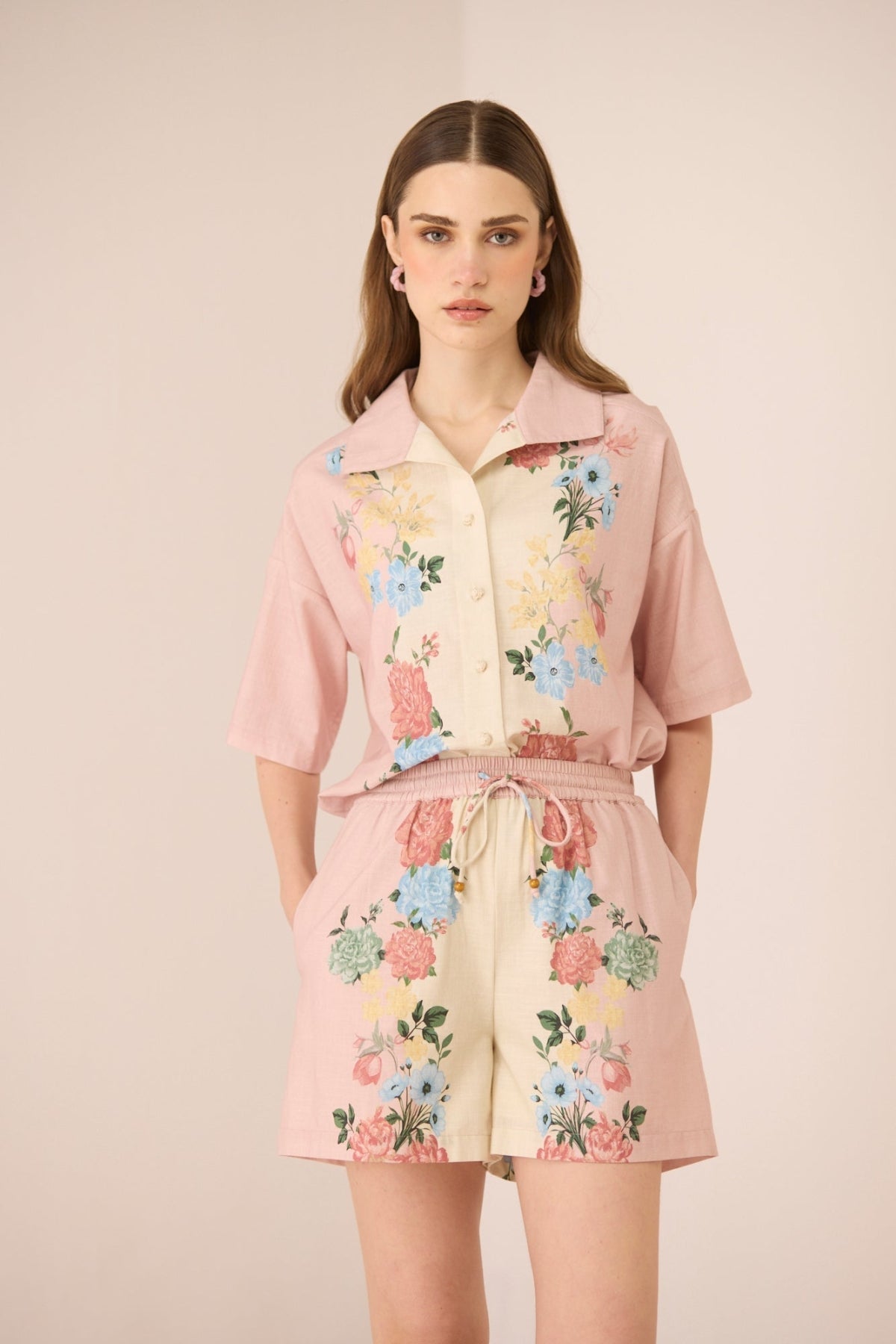 Woman wearing a pink floral outfit on a beige background Calling June