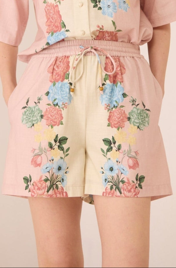 Woman wearing a pink floral outfit on a beige background Calling June