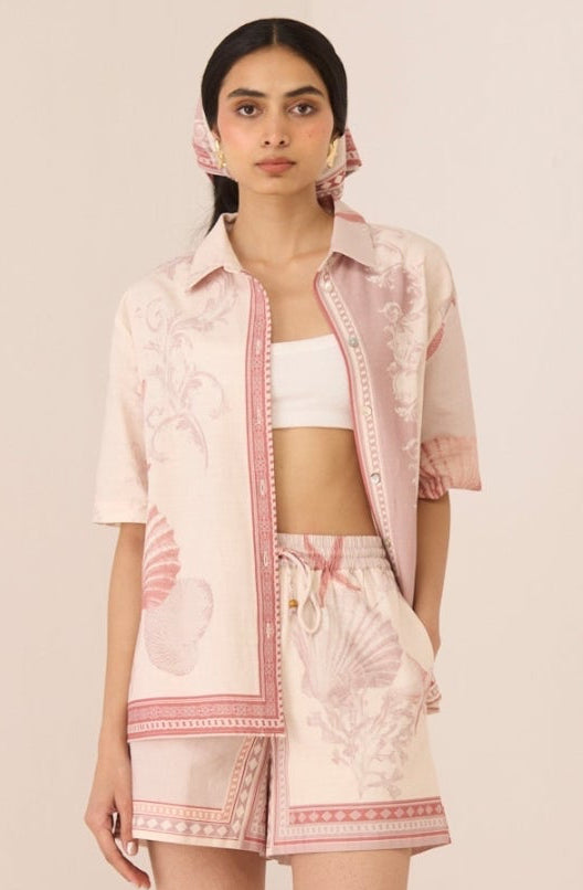Woman wearing a light pink outfit with a matching jacket on a plain background Calling June