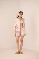 Woman wearing a light pink outfit with a matching scarf on a beige background Calling June