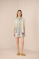 Woman wearing a light-colored outfit with denim accents on a beige background Calling June