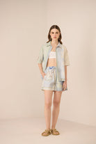 Woman wearing a light-colored outfit with a patterned skirt on a beige background Calling June