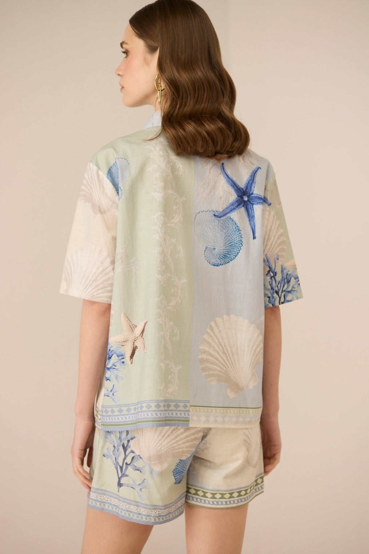 Woman wearing a short-sleeve top with marine-themed print on a beige background Calling June