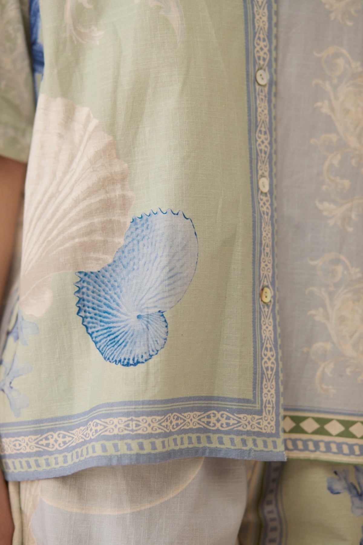 Light green fabric with blue shell design and intricate patterns Calling June