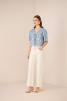 Woman wearing a blue floral blouse and white pants on a beige background Calling June