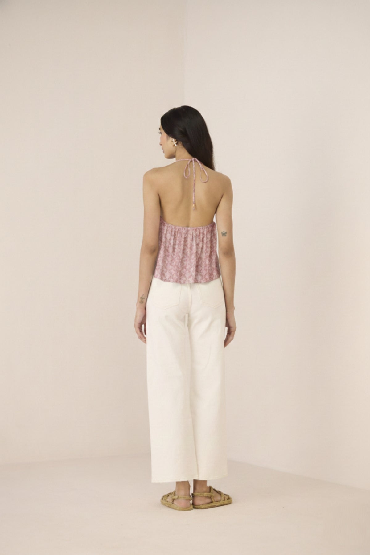 Woman wearing a patterned top and white pants on a beige background Calling June